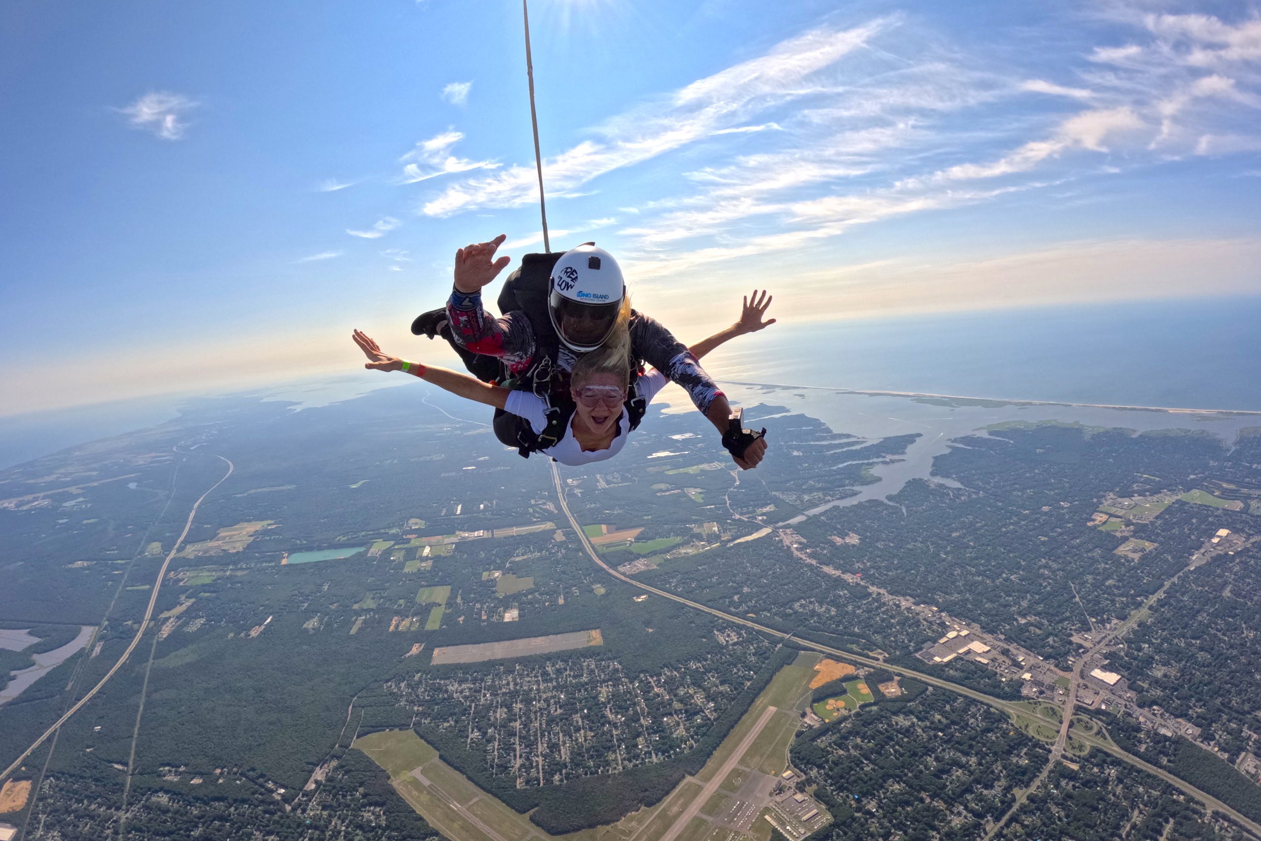 female tandem skydiving with instructor over beautiful view